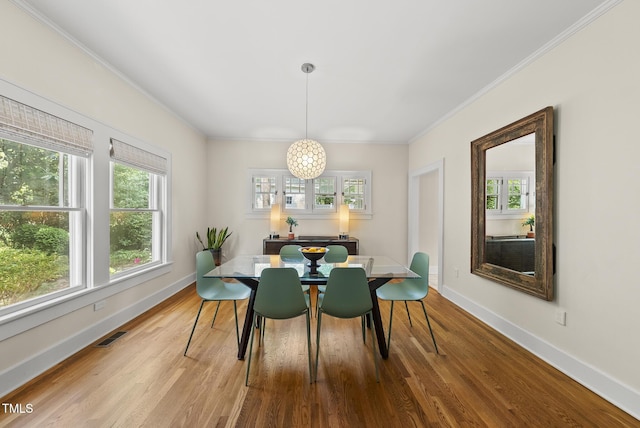 dining room featuring crown molding, plenty of natural light, wood finished floors, and visible vents