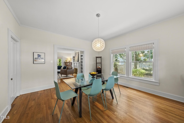 dining room featuring crown molding, baseboards, a healthy amount of sunlight, and wood finished floors