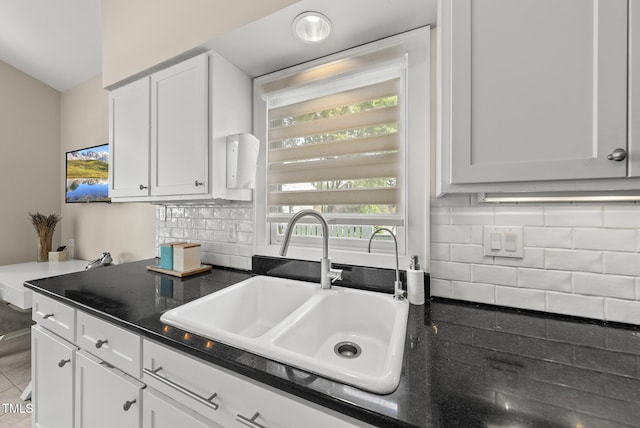 kitchen with a sink, white cabinetry, decorative backsplash, and dark countertops