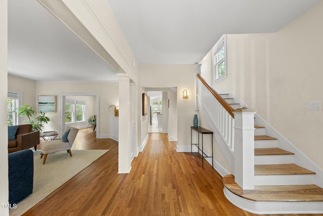 foyer entrance featuring baseboards, stairs, and wood finished floors