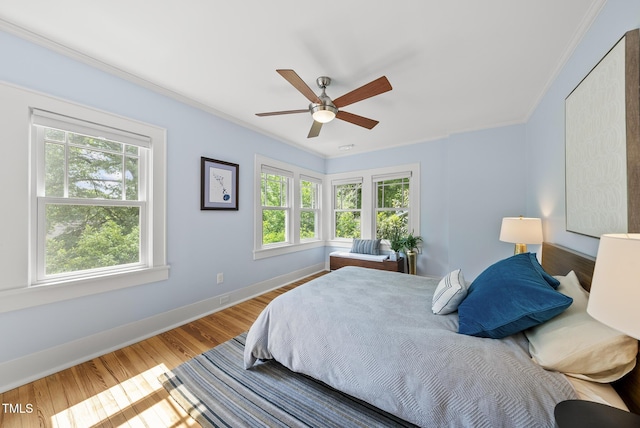bedroom featuring crown molding, baseboards, a ceiling fan, and wood finished floors
