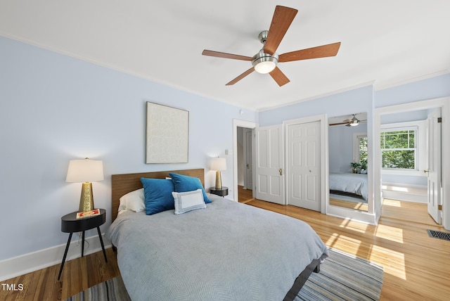bedroom with visible vents, light wood-style floors, crown molding, and baseboards