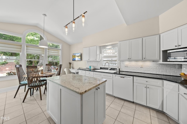 kitchen with white dishwasher, stainless steel microwave, a sink, light tile patterned floors, and vaulted ceiling