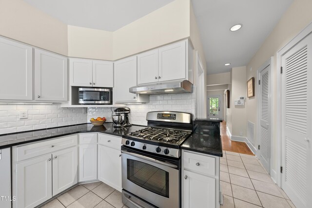kitchen featuring backsplash, stainless steel appliances, light tile patterned flooring, and under cabinet range hood