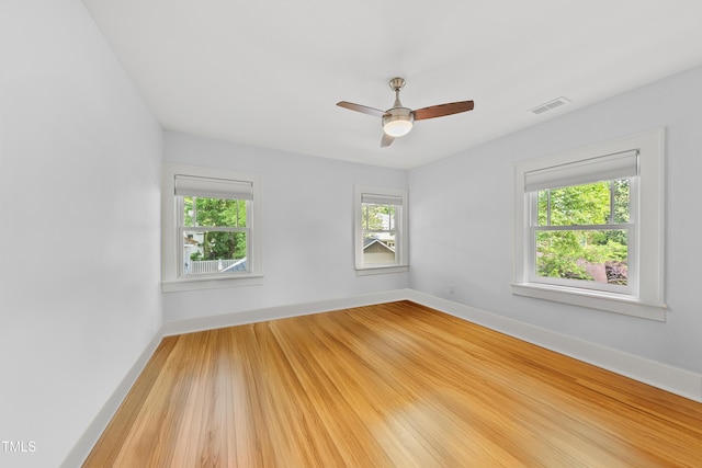 unfurnished room featuring light wood-style floors, a wealth of natural light, ceiling fan, and visible vents