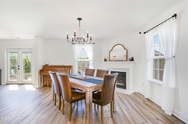 dining room featuring light wood-style flooring, an inviting chandelier, baseboards, and a fireplace