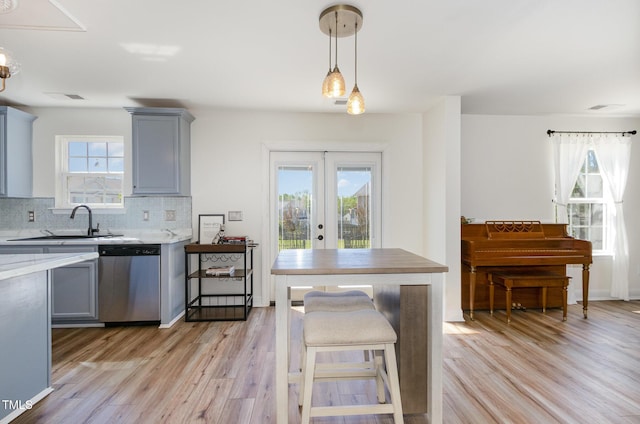 kitchen featuring gray cabinets, light countertops, backsplash, light wood-style floors, and dishwasher