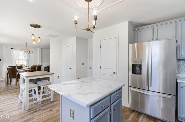 kitchen featuring hanging light fixtures, stainless steel refrigerator with ice dispenser, a notable chandelier, light wood-type flooring, and a kitchen island