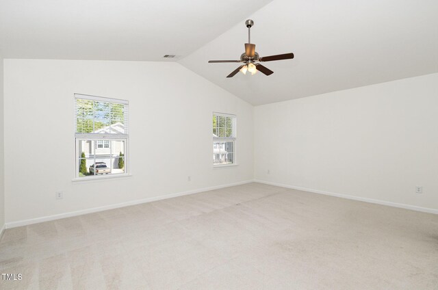 empty room with baseboards, vaulted ceiling, light carpet, visible vents, and ceiling fan