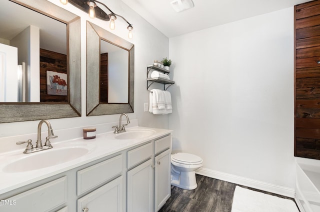 full bath featuring a sink, toilet, double vanity, and wood finished floors
