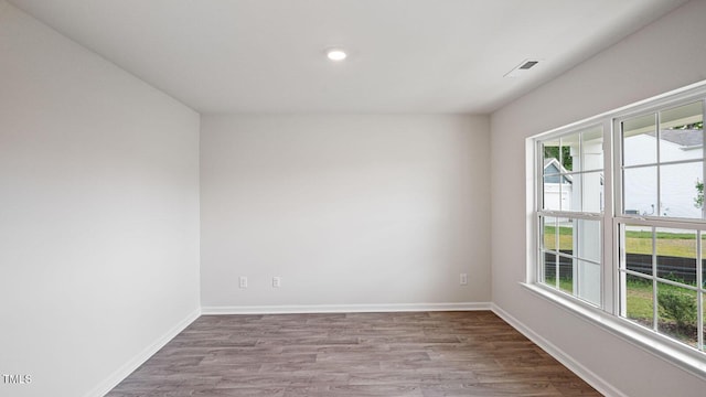 unfurnished room featuring wood finished floors, baseboards, and a wealth of natural light