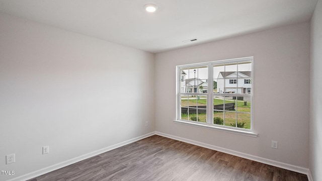 spare room featuring wood finished floors, baseboards, and visible vents