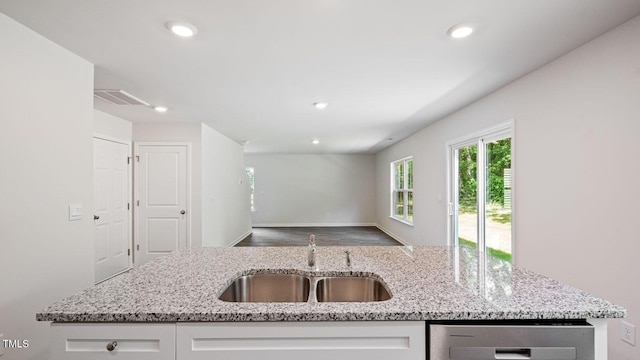 kitchen featuring visible vents, a sink, recessed lighting, white cabinetry, and light stone counters