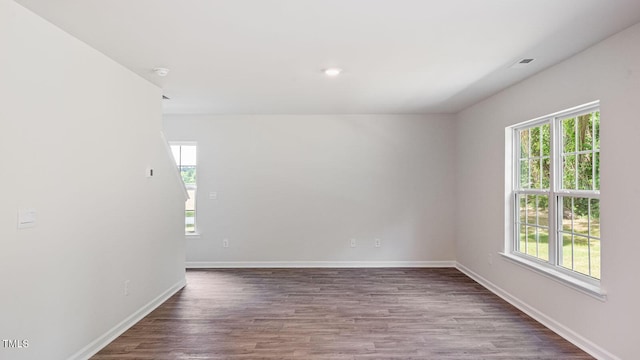 unfurnished room with a wealth of natural light, dark wood-style flooring, and baseboards