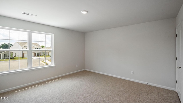 empty room with carpet flooring, visible vents, and baseboards