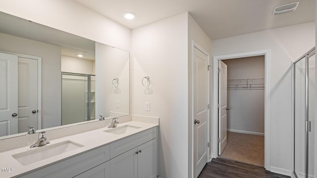 bathroom with a sink, visible vents, double vanity, and a stall shower