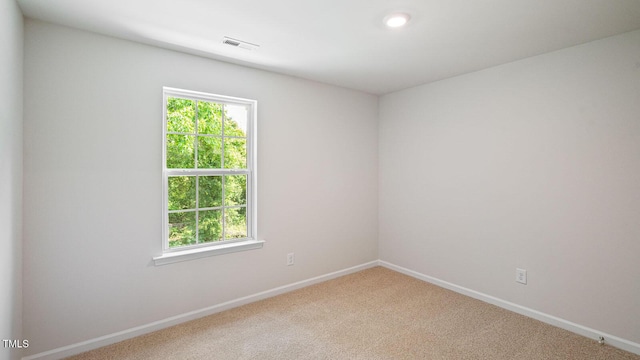 carpeted spare room with visible vents and baseboards
