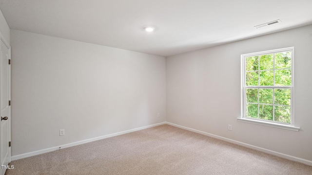 unfurnished room featuring light carpet, baseboards, visible vents, and a wealth of natural light