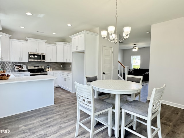1387 Stoney Creek Church Rd, Goldsboro, NC 27534 - kitchen featuring wood finished floors, ceiling fan with notable chandelier, white cabinetry, appliances with stainless steel finishes, and decorative backsplash