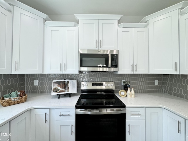 1387 Stoney Creek Church Rd, Goldsboro, NC 27534 - kitchen featuring white cabinets, decorative backsplash, stainless steel microwave, and electric stove