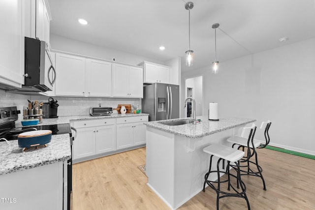 295 Springtooth Dr, Zebulon, NC 27597 - kitchen with stainless steel appliances, light wood finished floors, white cabinetry, and a sink