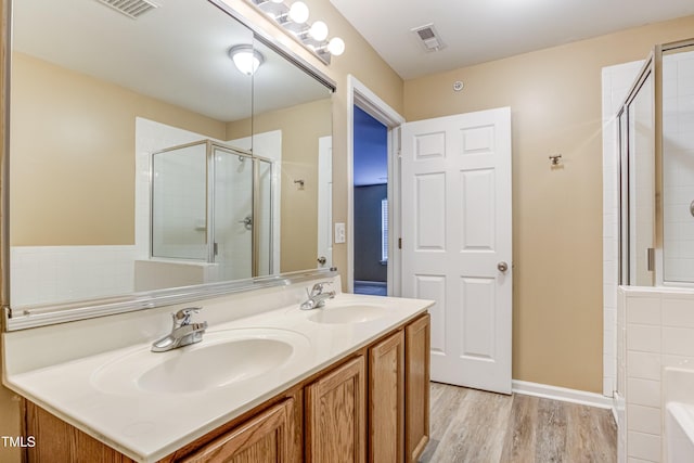 full bath featuring a stall shower, wood finished floors, a sink, and visible vents