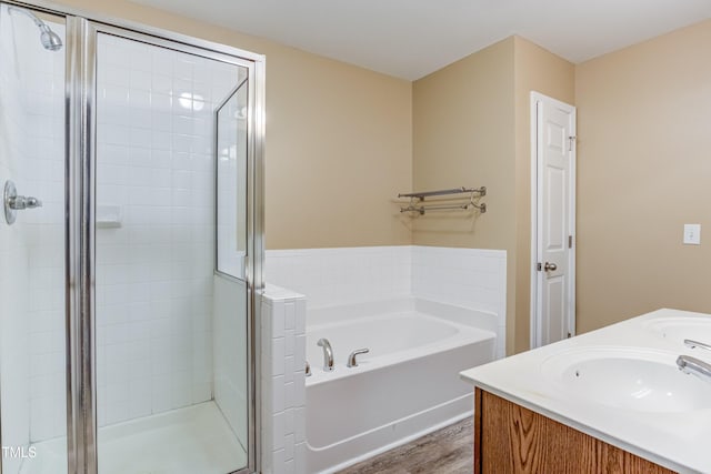 full bathroom featuring a bath, a sink, double vanity, wood finished floors, and a stall shower