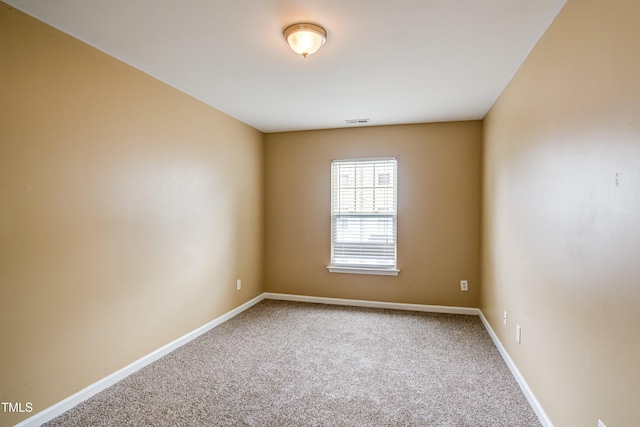 empty room with carpet flooring, visible vents, and baseboards