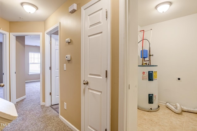 corridor with baseboards, carpet, and water heater