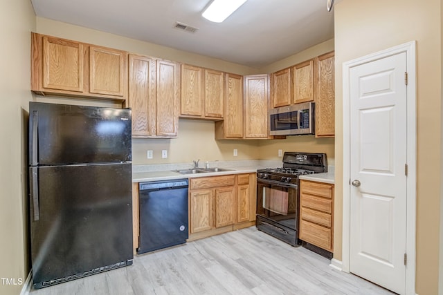 kitchen with light wood-type flooring, light countertops, black appliances, visible vents, and a sink