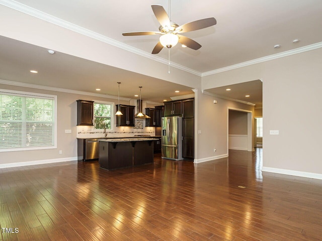 65 N Wilders Ridge Way, Clayton, NC 27527 - kitchen with appliances with stainless steel finishes, a kitchen breakfast bar, a kitchen island, dark brown cabinetry, and ornamental molding