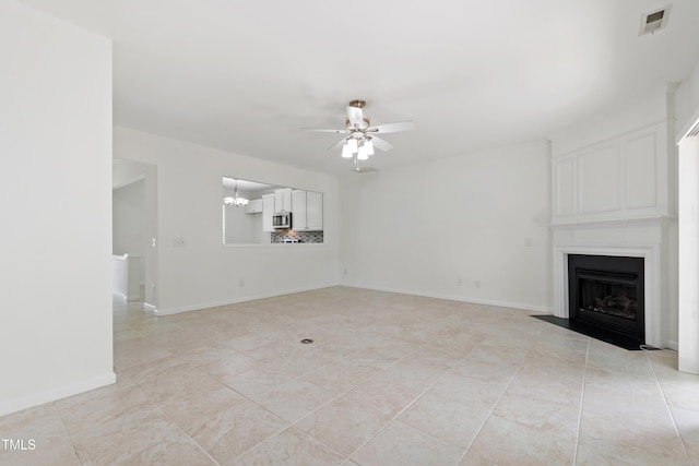unfurnished living room with a large fireplace, baseboards, ceiling fan with notable chandelier, and visible vents