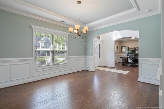 unfurnished dining area with a raised ceiling, arched walkways, a notable chandelier, and dark wood finished floors