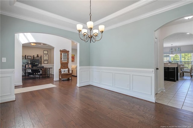 spare room featuring hardwood / wood-style floors, an inviting chandelier, and arched walkways
