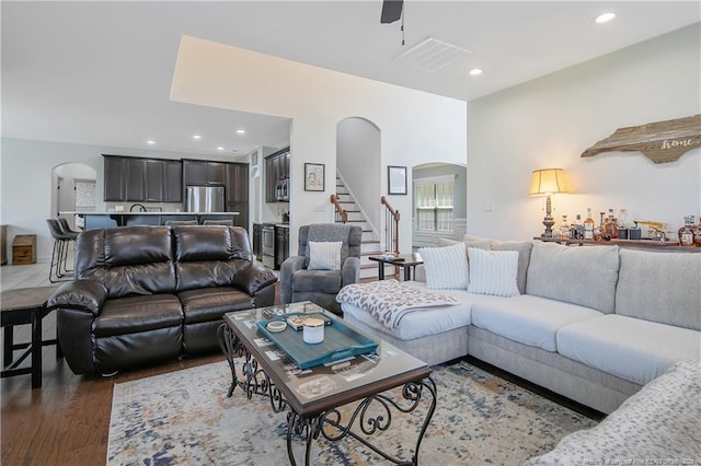 living area featuring arched walkways, wood finished floors, recessed lighting, and stairway