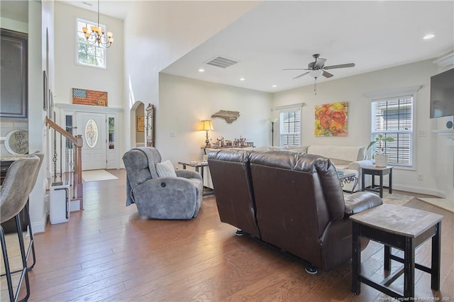 living area featuring visible vents, wood-type flooring, plenty of natural light, and ceiling fan with notable chandelier