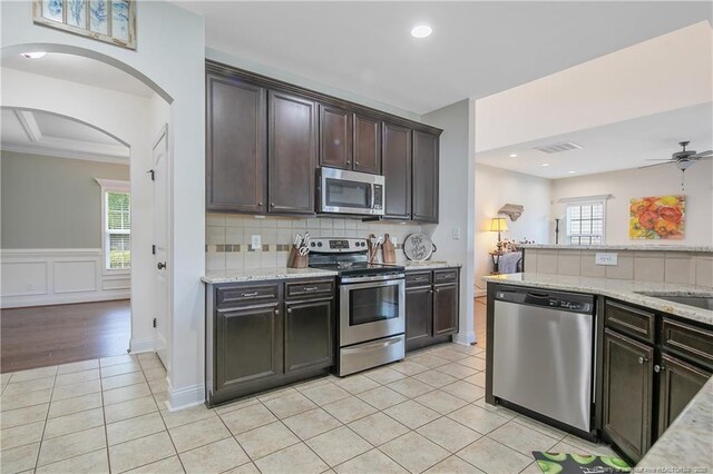 kitchen featuring visible vents, light tile patterned floors, arched walkways, appliances with stainless steel finishes, and dark brown cabinets
