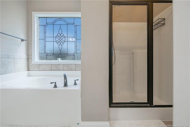 bathroom with a stall shower and a garden tub