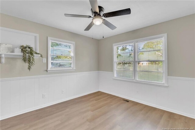 7517 Seaton Pl, Fayetteville, NC 28303 - spare room with visible vents, a ceiling fan, a wainscoted wall, and wood finished floors