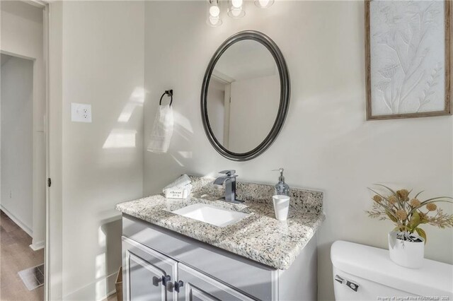 7517 Seaton Pl, Fayetteville, NC 28303 - bathroom with toilet, wood finished floors, vanity, and baseboards