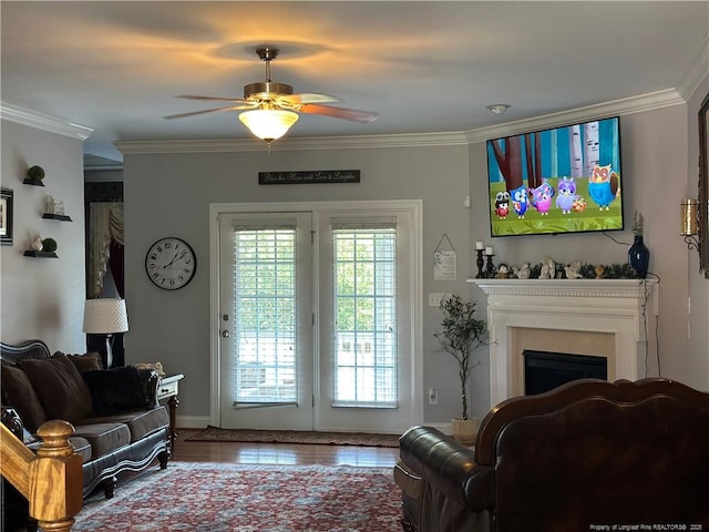 living area with ornamental molding, a ceiling fan, and a fireplace