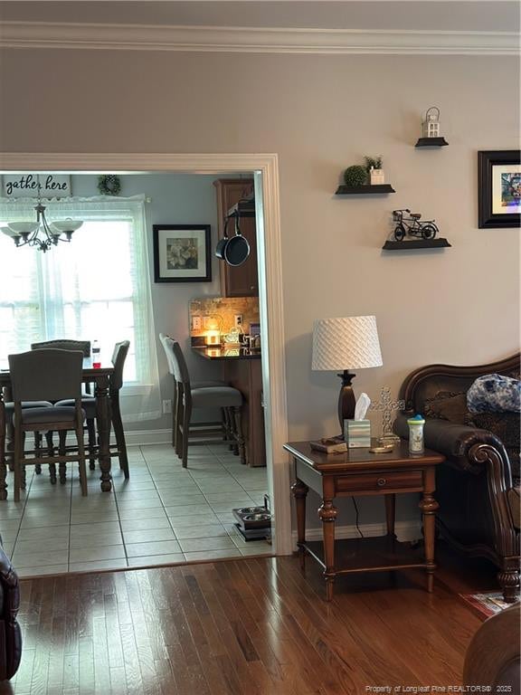 living room featuring ornamental molding, baseboards, a notable chandelier, and wood finished floors