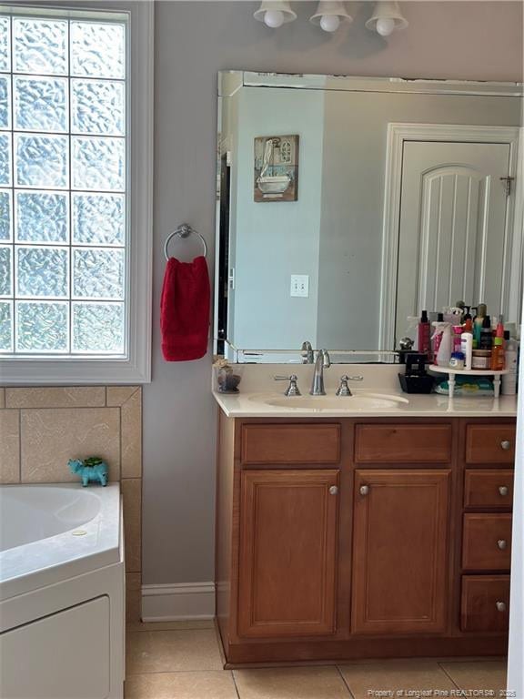 bathroom featuring tile patterned flooring, vanity, and a bath