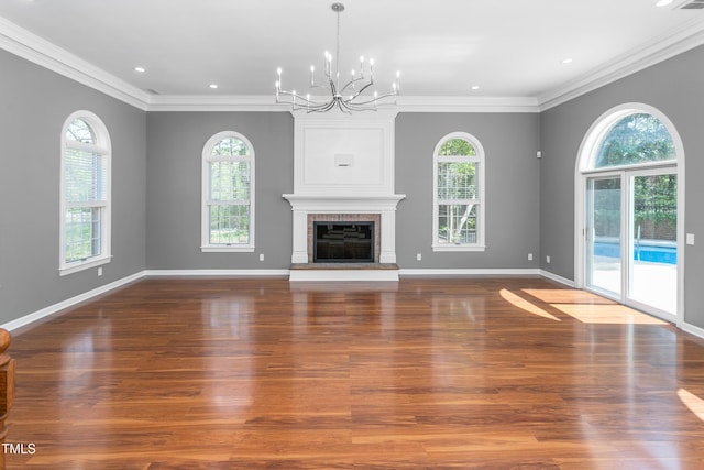 unfurnished living room featuring plenty of natural light, ornamental molding, and a notable chandelier