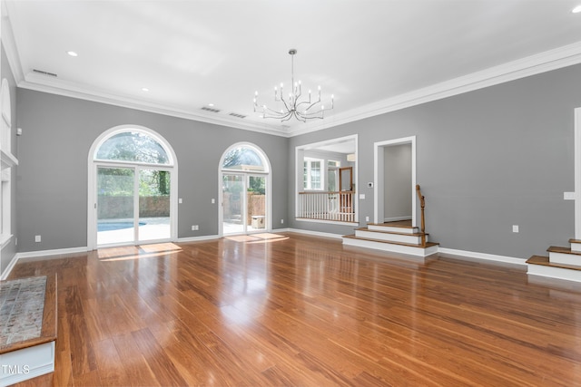unfurnished living room featuring crown molding, stairs, wood finished floors, and a notable chandelier