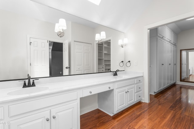bathroom with wood finished floors, double vanity, a sink, and a closet