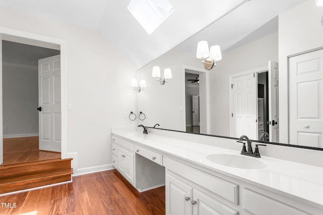 full bathroom with double vanity, a sink, wood finished floors, and vaulted ceiling with skylight