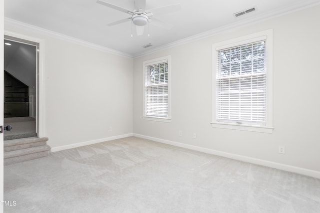 carpeted spare room featuring baseboards, ornamental molding, ceiling fan, and visible vents
