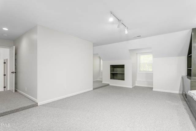 unfurnished living room with track lighting, baseboards, carpet flooring, and visible vents