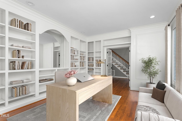 home office with crown molding, arched walkways, built in shelves, and dark wood-type flooring